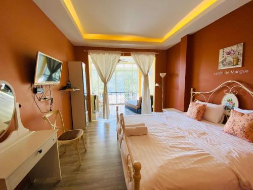 a bedroom with a large bed with orange walls at Jardin De Mangue Pakchong in Pak Chong