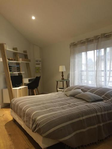 um quarto com uma cama, uma secretária e uma janela em La Bulle em Châlons-en-Champagne