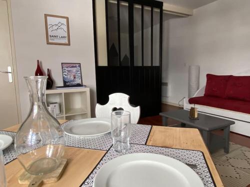 a table with white plates and a red couch in a living room at Vignec/Saint-Lary - T2 cosy avec balcon & piscine in Vignec