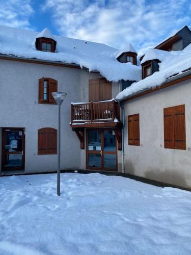 a building with snow on the roof and a balcony at Vignec/Saint-Lary - T2 cosy avec balcon & piscine in Vignec
