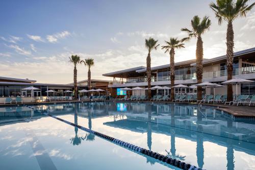 a swimming pool in front of a hotel with palm trees at Sun Outdoors San Diego Bay in Chula Vista