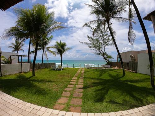 a walkway leading to the beach with palm trees at Porto Paraiso Hostel in Porto De Galinhas