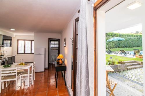 a kitchen and dining room with a view of a yard at Apartamento do Pinheiro (with Shared Swimming Pool) in São Vicente Ferreira