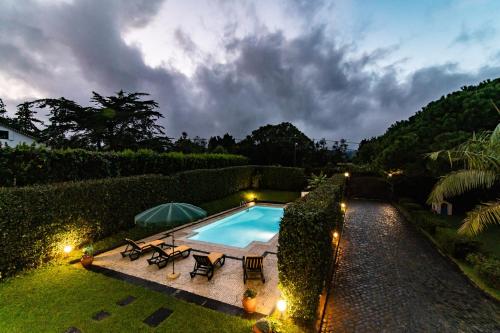 an overhead view of a swimming pool with chairs and an umbrella at Apartamento do Pinheiro (with Shared Swimming Pool) in São Vicente Ferreira