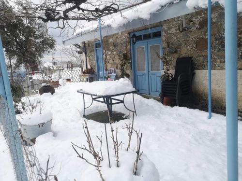 a snow covered yard with a table and a blue door at Holiday House Prodromos in Prodromos