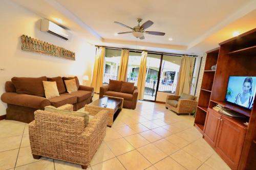 a living room with a couch and a tv at Monte Carlo Luxury Condominiums in Jacó