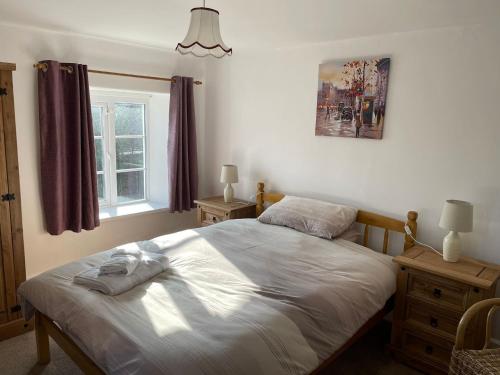a bedroom with a bed and a window at Stibb Farm Cottage at Sandymouth in Bude