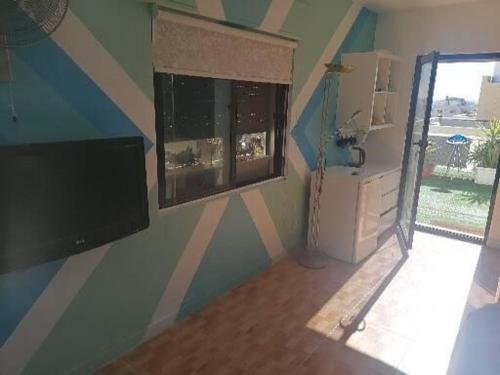 a room with a wall with a television and a window at Rooftop one room in Amman