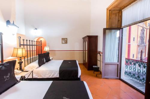 a bedroom with two beds and a large window at Hotel de la Paz in Guanajuato