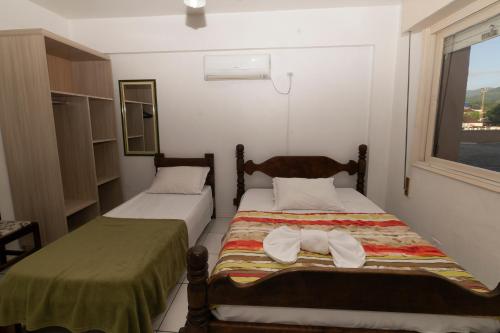 two beds in a small room with a window at Hotel Igrejinha in Igrejinha