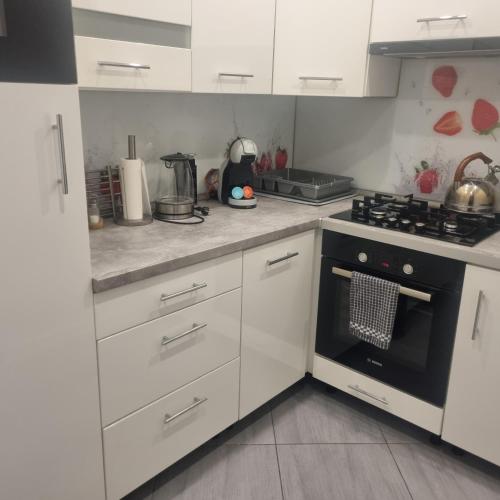 a kitchen with white cabinets and a black oven at Noclegi FAMILY APARTMENTS Hotel Apartamenty in Racibórz