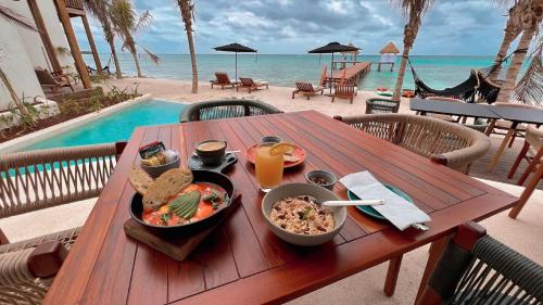 a wooden table with a bowl of food and a drink on the beach at Nerea Tulum in Tulum