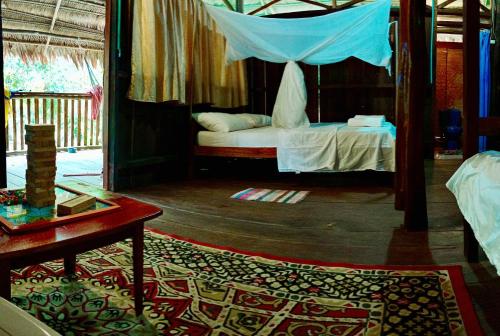 a bedroom with a bed with a canopy and a table at Bungalow In The Jungle -Ecolodge HUITOTO in Leticia