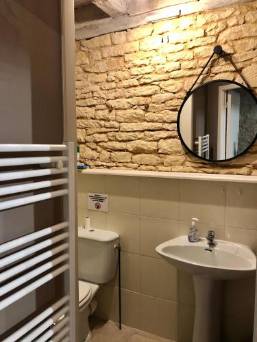 une salle de bain avec un lavabo, des toilettes et un miroir dans l'établissement Le Moulin Aux Ans, à Archignac