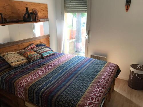 Un dormitorio con una cama con un edredón colorido y una ventana en Le Dakar - T2 avec Parking offert, en Toulouse