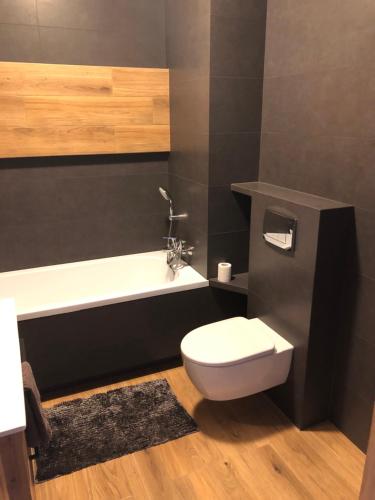 a bathroom with a white toilet and a bath tub at Apartament Chopina in Łomianki