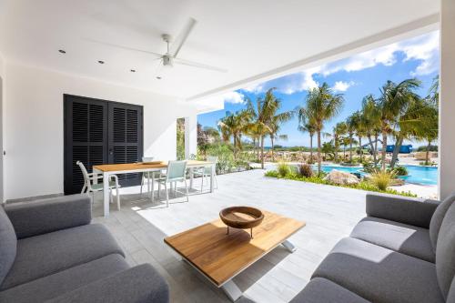 a living room with a dining table and a view of the ocean at The Reef - Blue Bay Golf & Beach Resort in Willemstad
