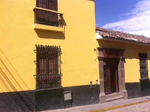 a yellow building with a balcony and a window at Hostal Tres Máscaras in Ayacucho