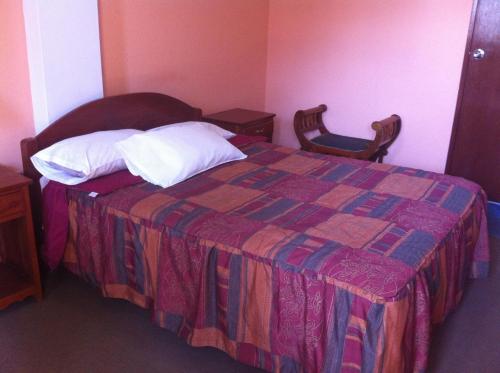 a bedroom with a bed with a quilt and two pillows at Hostal Tres Máscaras in Ayacucho