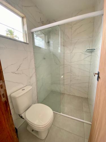 a bathroom with a toilet and a glass shower at Santo Mar Em São Miguel do gostoso in Touros
