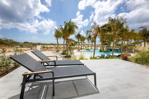 a couple of chairs sitting on a patio with a pool at The Reef - Blue Bay Golf & Beach Resort in Willemstad
