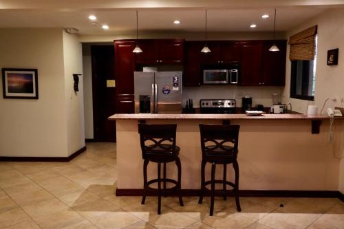 a kitchen with two bar stools and a refrigerator at Monte Carlo Luxury Condominiums in Jacó