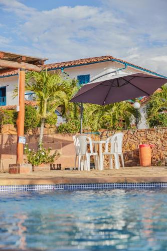 two chairs and an umbrella next to a swimming pool at Hotel Santos De Piedra - MARANATHA BARICHARA in Barichara