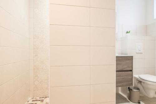 a white bathroom with a toilet and a shower at Centre - Le Cloud - Parking in Drulingen