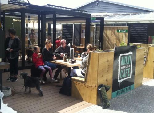 a group of people sitting at a table outside a restaurant at Beachpoint Apartments in Ohope Beach