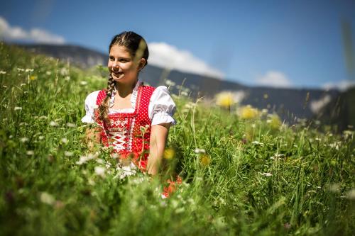a young girl is walking through a field of flowers at Apart Mado in Längenfeld