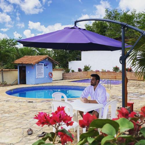a man sitting at a table under an umbrella at Hotel Santos De Piedra - MARANATHA BARICHARA in Barichara