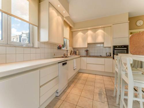 a kitchen with white cabinets and a large window at Heers Retreat with Sauna in Heers