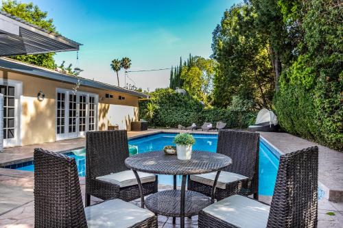a patio with a table and chairs next to a swimming pool at Villa Sausalito - Newly Designed 4BR HOUSE & POOL by Topanga in Los Angeles