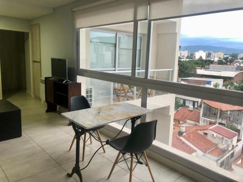 mesa y sillas en una habitación con ventana grande en Dean Funes Suites 607 en Salta