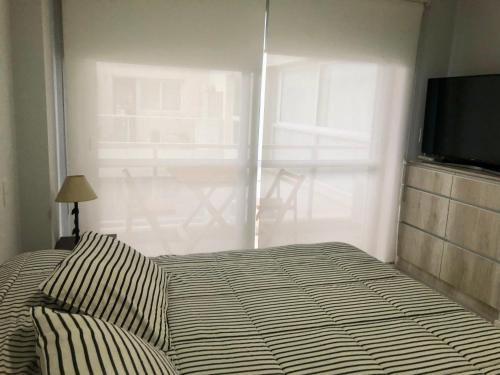 1 dormitorio con 1 cama, TV y ventana en Dean Funes Suites 607 en Salta