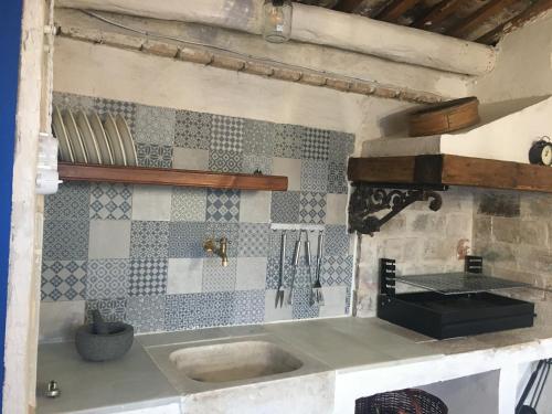 een keuken met een wastafel en een betegelde muur bij Cal Sabater in Preixana
