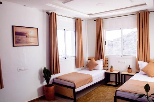 1 dormitorio con 2 camas y 2 ventanas en Mouja Surf Camp en Taghazout