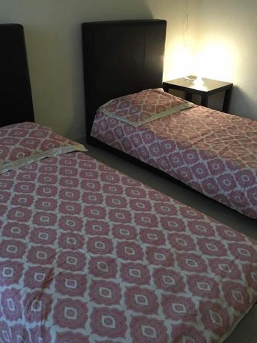 two beds sitting next to each other in a room at KS Lavender Kuala Kangsar in Kuala Kangsar