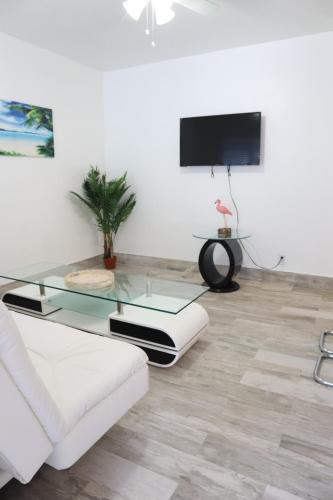 a living room with a glass table and a tv at SII Luxury 1 Bedroom close to the beach in West Palm Beach