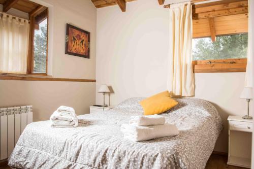 Un dormitorio con una cama con toallas. en Cabañas Las Donosas, en San Carlos de Bariloche