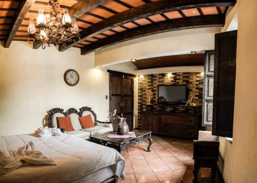 ein Wohnzimmer mit einem Bett und einem TV in der Unterkunft Casa Catalina in Antigua Guatemala