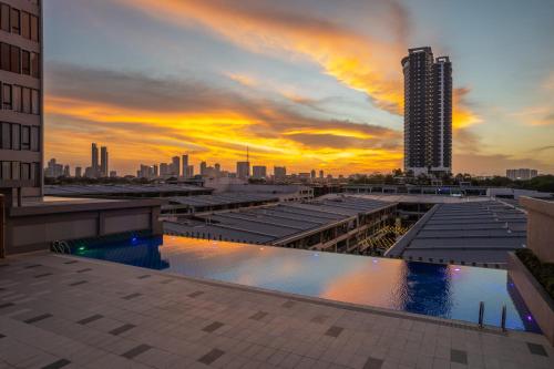 een uitzicht op de skyline van de stad bij zonsondergang met een zwembad bij Opero Hotel Southkey Johor Bahru in Johor Bahru