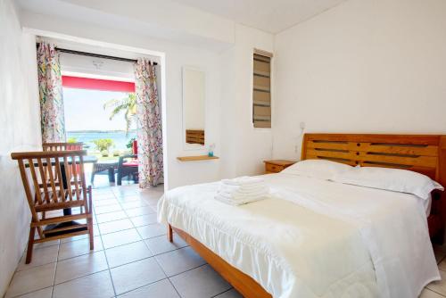 1 dormitorio con 1 cama, 1 silla y 1 ventana en Colibri Beach Villas, en Trou d'Eau Douce