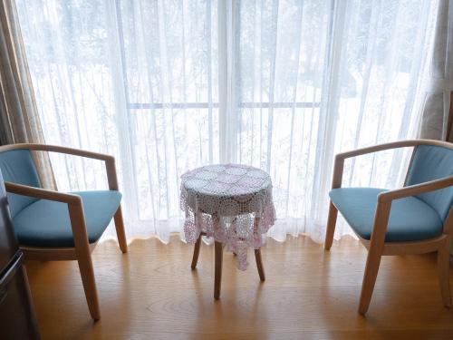 una mesa y dos sillas frente a una ventana en みんなの実家門脇家, en Akita