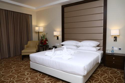 a hotel room with a large white bed and a chair at YN Hotels in Bengaluru