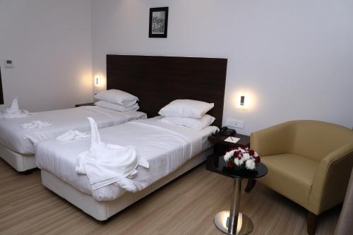 a hotel room with two beds and a chair at YN Hotels in Bengaluru