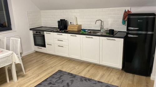 a kitchen with white cabinets and a black refrigerator at Center House in Ramingstein