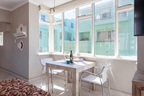 a dining room with a table and chairs and a window at Cosy and Classy Sea Point Apartment in Cape Town