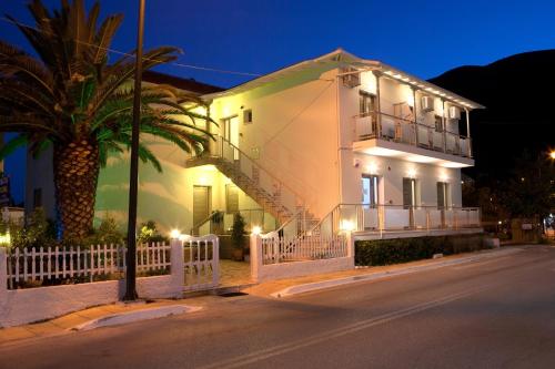 a white house with a palm tree in front of it at Savinos Rooms in Vasiliki