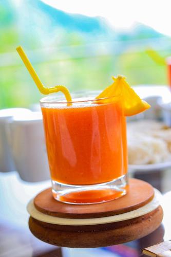 a drink sitting on a wooden coaster with an orange drink at Flaming Tree Resorts in Kiriwan Eliya